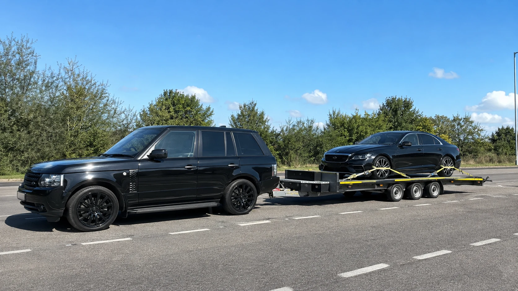 Car being transported on a tri-axle vehicle trailer